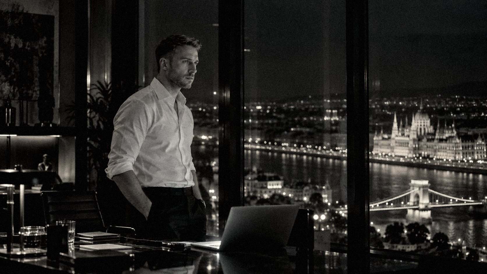 Balázs Schultz by a laptop at a dark office window above the Danube at night